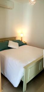 a bedroom with a large white bed with a lamp at L'albizia Studio calme et tout confort in Lucciana