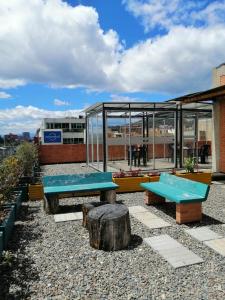 eine Terrasse mit blauen Bänken und einem Glasgebäude in der Unterkunft Bien ubicado, cómodo y funcional in Bogotá