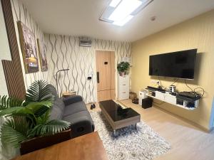 ein Wohnzimmer mit einem Sofa und einem Flachbild-TV in der Unterkunft คอนโด รังสิตใกล้ฟิวเจอร์พาร์ค 1 ห้องนอน in Ban Talat Rangsit