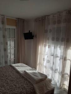 1 dormitorio con 1 cama y una ventana con cortinas en Piso encantador Mediterráneo, en Rincón de la Victoria