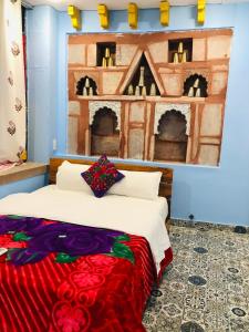 a bedroom with a bed and a painting on the wall at Swiss House in Jodhpur