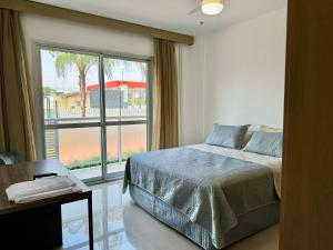 a bedroom with a bed and a large window at Suite privativa na Barra da Tijuca, RJ - Neolink Stay in Rio de Janeiro