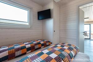 two beds in a room with a tv on the wall at Hausboot Harmonie in Stralsund