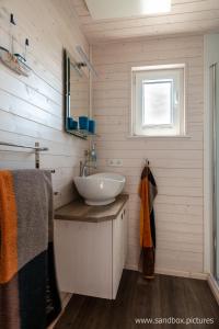 a bathroom with a white sink and a window at Hausboot Harmonie in Stralsund