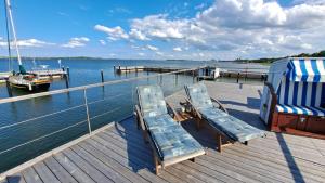 a dock with two lounge chairs and a boat at Hausboot Harmonie in Stralsund