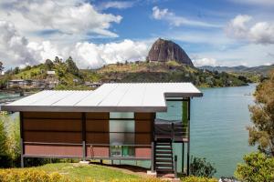 una casa en un lago con una montaña en el fondo en Cabañas Navegar- El peñol, Guatape, en Guatapé