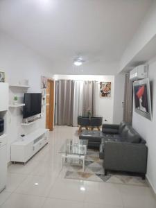 a living room with a black couch and a tv at El mejor apartamento cerca de la playa de Boca Chica in Boca Chica