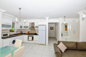 a kitchen and living room with white cabinets and a couch at The Royal Links two bedroom apartment in Ortaca