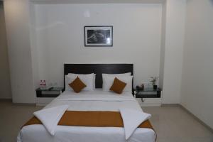 1 dormitorio con 1 cama grande con sábanas y almohadas blancas en Hotel Sai Bansi, en Shirdi