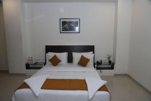 a bedroom with a large bed with white sheets and pillows at Hotel Sai Bansi in Shirdi