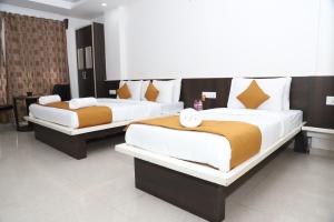 two beds in a hotel room withskirts at Hotel Sai Bansi in Shirdi