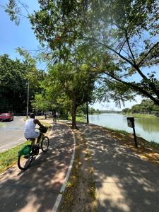 a man riding a bike down a path next to a lake at Pampulha 2 quartos completo in Belo Horizonte