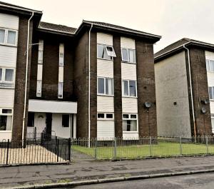 ein Apartmenthaus mit einem Zaun davor in der Unterkunft Take A Break and Unwind At This Peaceful Home in Saltcoats