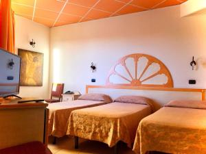 サン・ボニファーチョにあるHotel Villabellaのベッド3台とテレビが備わるホテルルームです。