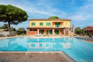 a large swimming pool in front of a house at Ombra Verde Residence e B&B in Follonica