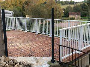 a wooden deck with white railings on a house at La petite maison in Putanges