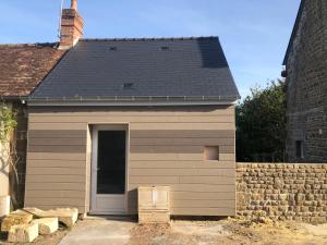 a small building with a door and a brick wall at La petite maison in Putanges-le-Lac