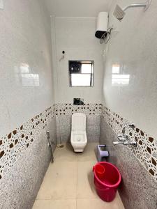 a bathroom with a toilet and a red bucket at 5bhk- Nature Villa in Lonavala