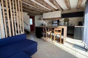 Il comprend un salon avec un canapé bleu et une cuisine. dans l'établissement Maison à proximité du village de George Sand, à Nohant-Vic