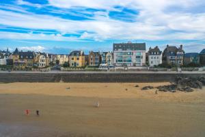 people walking on the beach with buildings in the background at Hôtel Les Charmettes - Saint Malo in Saint Malo
