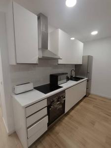 cocina con armarios blancos y fogones en Encantador apartamento completo con dos habitaciones, en Madrid