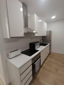 cocina con armarios blancos y encimera en Encantador apartamento completo con dos habitaciones, en Madrid