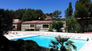 a swimming pool with white chairs and a house at T2 avec piscine et accès privé à la mer in Sanary-sur-Mer