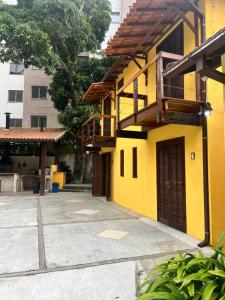 a yellow building with a balcony and a patio at Villa Aconchego Corrêas Itaipava in Petrópolis