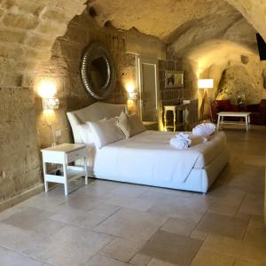 um quarto com uma cama e um sofá numa sala de pedra em Caveoso Hotel em Matera