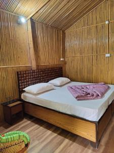 ein Schlafzimmer mit einem Bett in einem Holzzimmer in der Unterkunft Moupiya Resort and Restaurant in Dāngchura