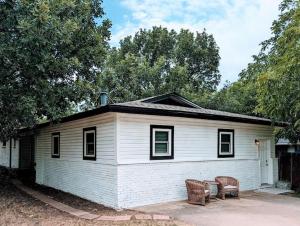 ein weißes Haus mit zwei Bänken davor in der Unterkunft Cozy Family Home in Texas in Fort Worth