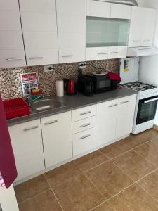 a kitchen with white cabinets and a sink and a stove at White&Red Apartments in Timişoara