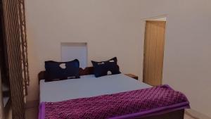 um quarto com uma cama grande e lençóis roxos em Tiger Guest House & Restaurant em Sawai Madhopur