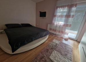 a bedroom with a bed and a television and a window at Apartman Samantha in Vinkovci