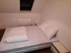 ein Bett mit weißen Laken und Kissen in einem Zimmer in der Unterkunft Agréable maison de pêcheurs avec parking gratuit. in Grand-Fort-Philippe