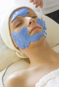 a woman with a blue mask on her face with a toothbrush at Łeba Hotel & Spa in Łeba