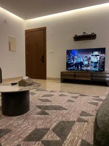 sala de estar con TV grande y mesa en شقه فلاتس الماجدية, en Riad