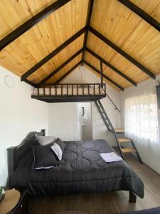 1 dormitorio con cama negra y techo de madera en Hospedaje - Cabañas villa rosita, en Monguí