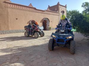 dos personas montando en ATvs en frente de un edificio en KASBAH IFRi, en Amdnarene