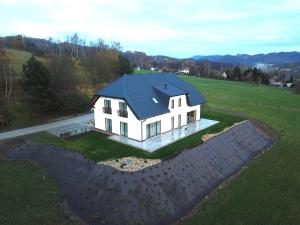 a white house with a blue roof on a field at Apartmány Semily in Semily