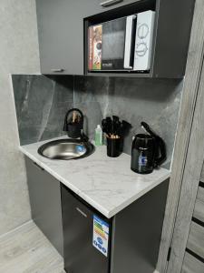 a kitchen counter with a sink and a microwave at Apart 41 in Almaty