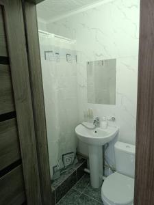 a white bathroom with a toilet and a sink at Apart 41 in Almaty