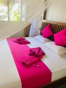 Una cama con sábanas rosas y batas rosas. en Villa Riverside en Aluthgama