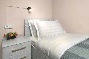 een witte slaapkamer met een bed en een plant op een dressoir bij Guesthouse Liliia in Karakol