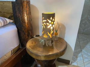 a lamp on a wooden table next to a bed at Suíte BOTOS DE ALTER in Alter do Chao