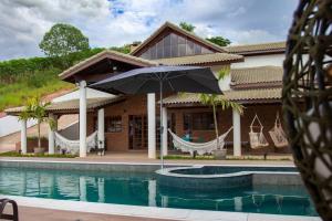 une maison avec un hamac en face d'une piscine dans l'établissement Recanto Gabi Mafê., à Igaratá