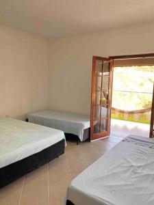 Cette chambre comprend 2 lits et une fenêtre. dans l'établissement Recanto Gabi Mafê., à Igaratá