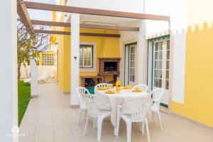 a white table and chairs on a patio with a fireplace at Santa Beach Villa - 3 bedrooms & BBQ in Santa Cruz