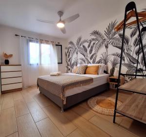 a bedroom with a bed with a tropical wallpaper at Le Cyprès, billard piscine et jacuzzi, classé 4 étoiles in Saint-Joseph