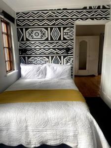 Milner Cottage: Digital Nomad Oasis في كيب تاون: غرفة نوم بسرير كبير وبجدار